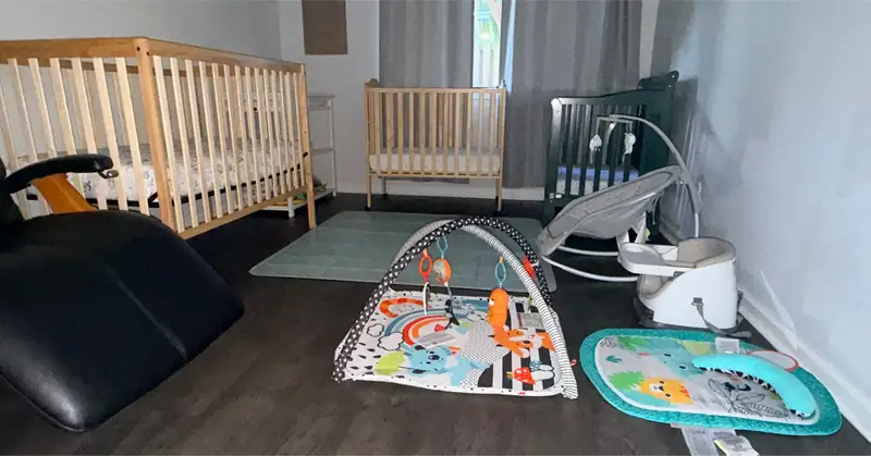 Wide view of the Little Roots infant care room with cribs and age-appropriate play equipment