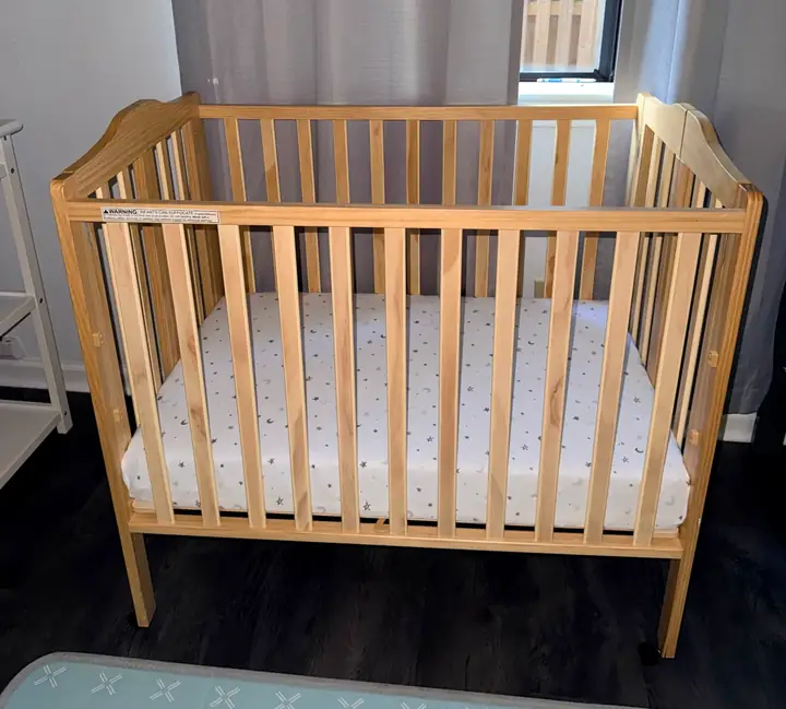 Prepared infant crib with a fitted sheet in the Little Roots care room